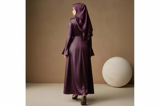 Woman wearing a long, dark purple dress against a beige background