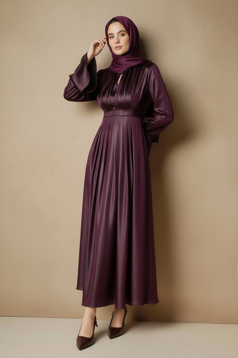 Woman wearing a long purple dress against a beige wall