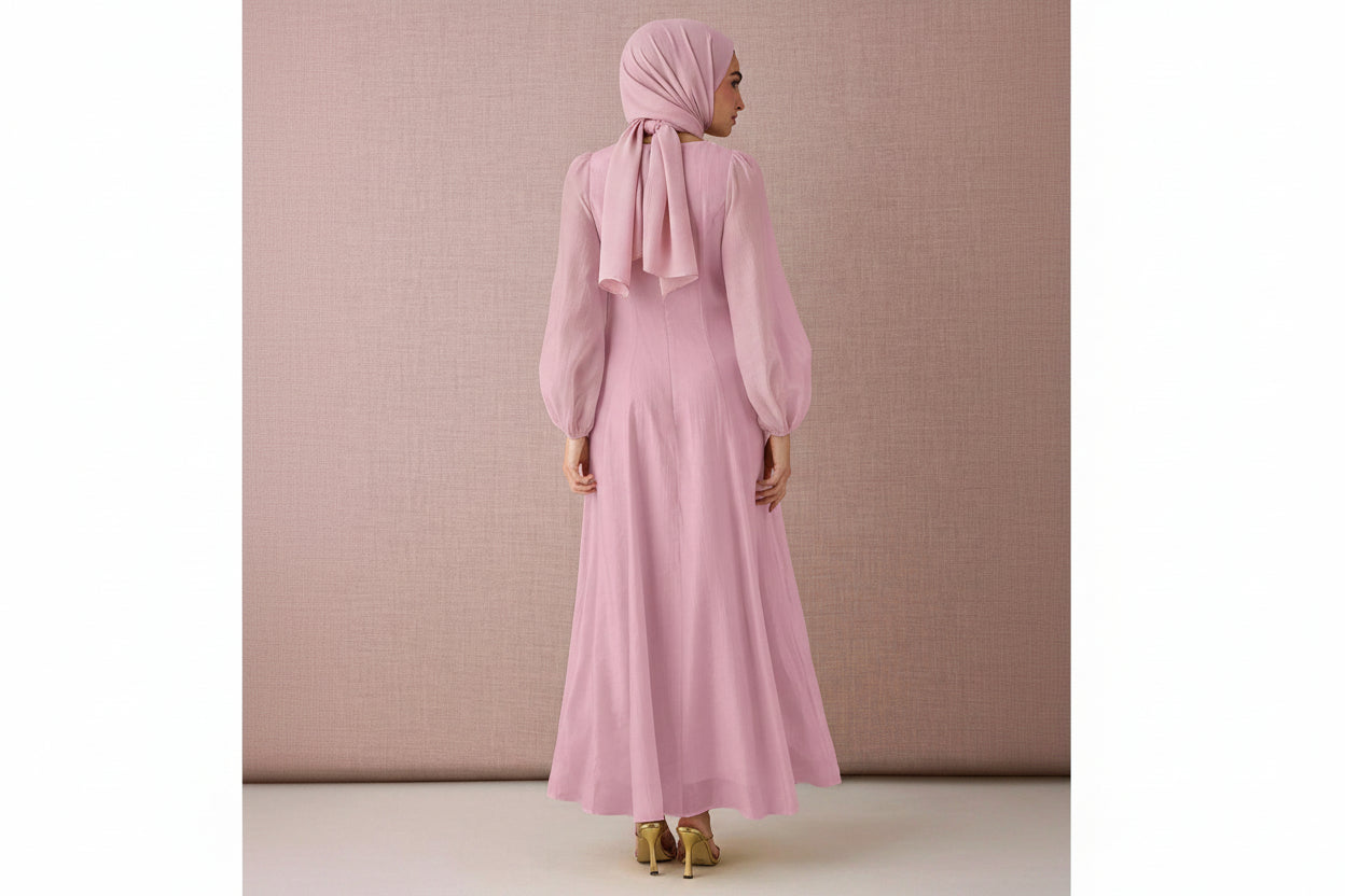 Woman wearing a pink dress with long sleeves against a beige background