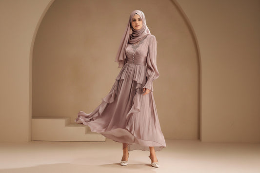 Woman wearing a flowing lavender dress against a beige background