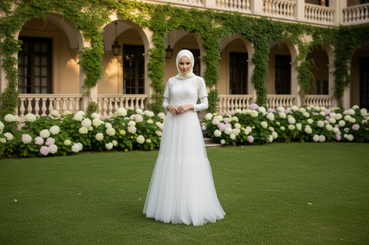 Woman in a white dress standing in front of an ivy-covered building with floral arrangements.